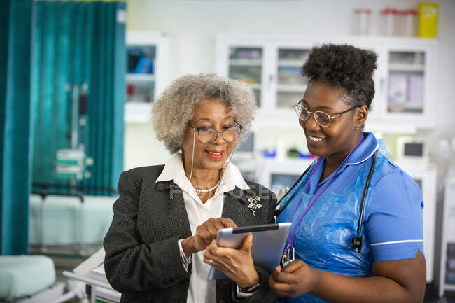 Médica e enfermeira usando tablet digital no hospital — Fotografia de Stock