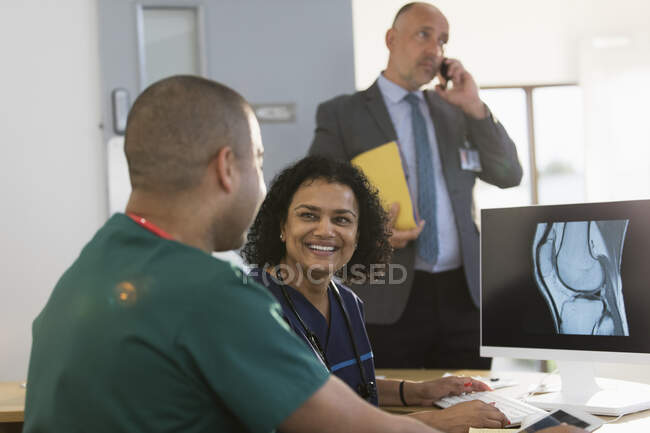 Enfermeiros sorridentes discutindo raio-x digital no computador na clínica — Fotografia de Stock