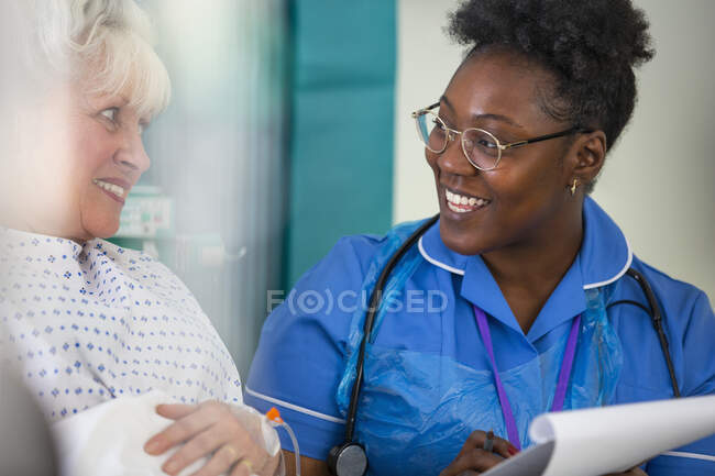 Дружелюбная медсестра разговаривает со старшим пациентом в больнице — стоковое фото