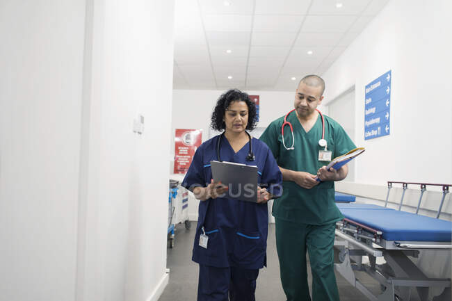 Médicos con historial médico haciendo rondas en corredor hospitalario - foto de stock