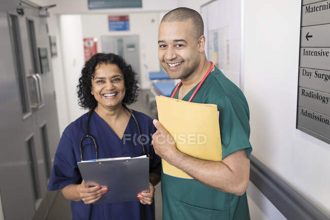 Retrato médicos confiantes com prontuário fazendo rondas no corredor do hospital — Fotografia de Stock