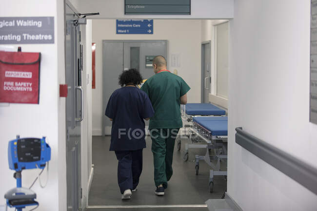 Médico e cirurgião caminhando no corredor hospitalar — Fotografia de Stock