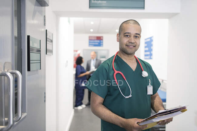 Портрет впевненого лікаря-чоловіка з медичною картою, що робить раунди в лікарняному коридорі — стокове фото