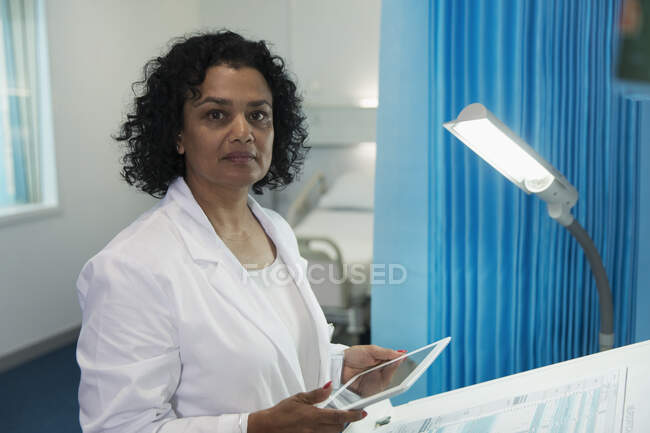 Portrait confiant, déterminé femme médecin en utilisant tablette numérique dans la chambre d'hôpital — Photo de stock