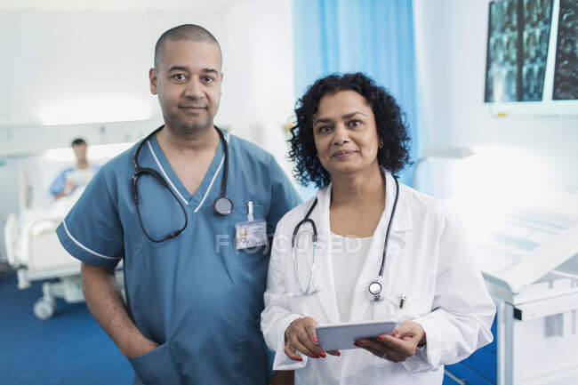 Портрет уверенный врач и медсестра с цифровой таблеткой в больничной палате — стоковое фото