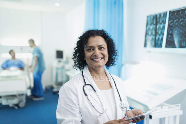 Улыбающаяся, уверенная в себе женщина-врач с цифровым планшетом в больничной палате — стоковое фото