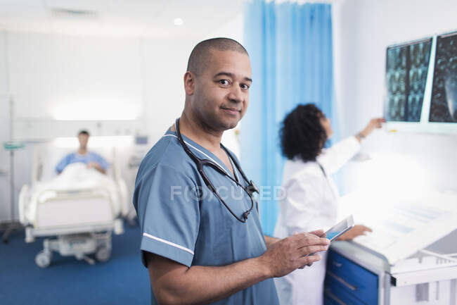 Retrato seguro, médico sonriente usando tableta digital en la habitación del hospital - foto de stock