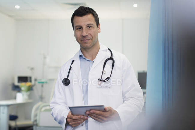 Porträt selbstbewusster männlicher Arzt mit digitalem Tablet im Krankenhauszimmer — Stockfoto