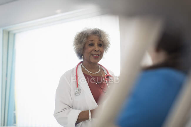 Médica sênior fazendo rondas, conversando com paciente no quarto do hospital — Fotografia de Stock