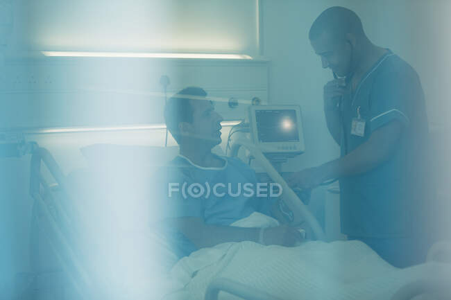 Медбрат со стетоскопом осматривает пациента на больничной койке — стоковое фото