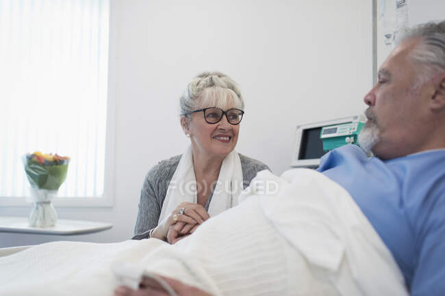 Prendersi cura di una donna anziana in visita, confortante marito che riposa nel letto d'ospedale — Foto stock