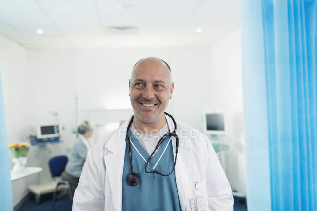 Retrato seguro, sonriente médico masculino en la habitación del hospital - foto de stock