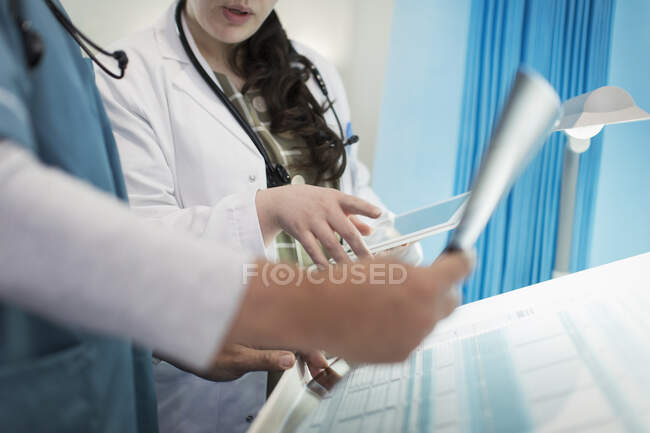 Médicos con tableta digital discutiendo rayos X en la habitación del hospital - foto de stock