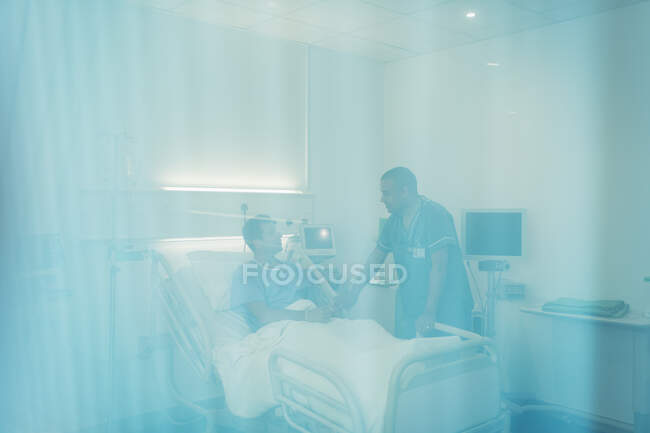 Медбрат разговаривает с пациентом в больничной палате — стоковое фото