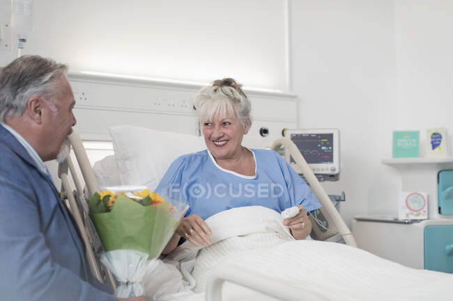 Uomo anziano con mazzo di fiori in visita moglie in ospedale — Foto stock