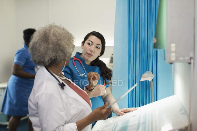 Женщина-врач и медсестра с цифровым планшетом разговаривают в больничной палате — стоковое фото