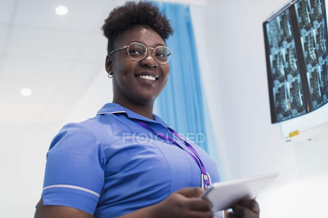 Enfermera confiada en retratos con tableta digital examinando rayos X en la habitación del hospital - foto de stock