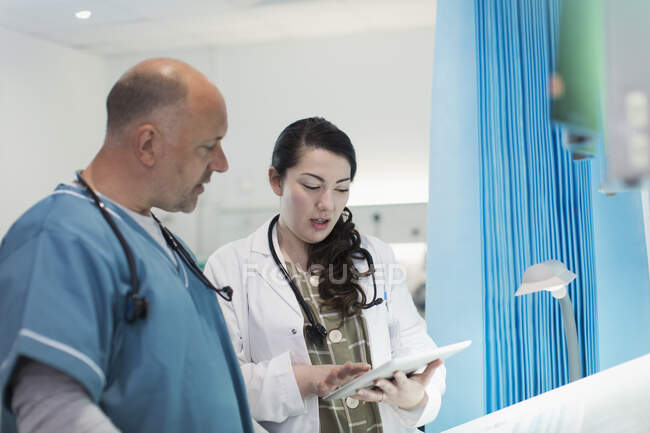 Médicos com tablet digital conversando no quarto do hospital — Fotografia de Stock