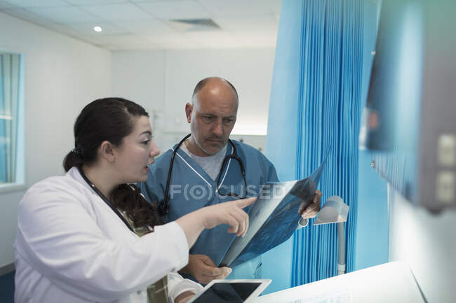 Médicos discutiendo rayos X en la habitación del hospital - foto de stock
