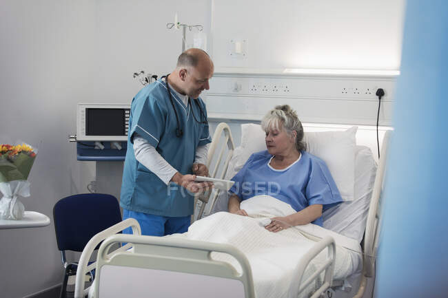 Medico con tablet digitale fare giri, parlando con il paziente anziano in camera d'ospedale — Foto stock