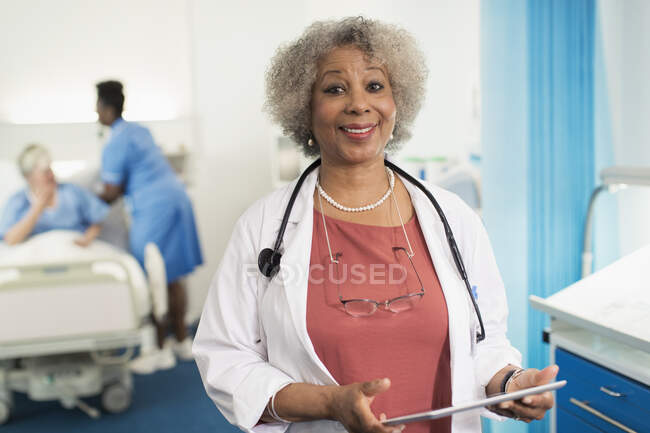 Ritratto medico donna anziana fiduciosa utilizzando tablet digitale in camera d'ospedale — Foto stock
