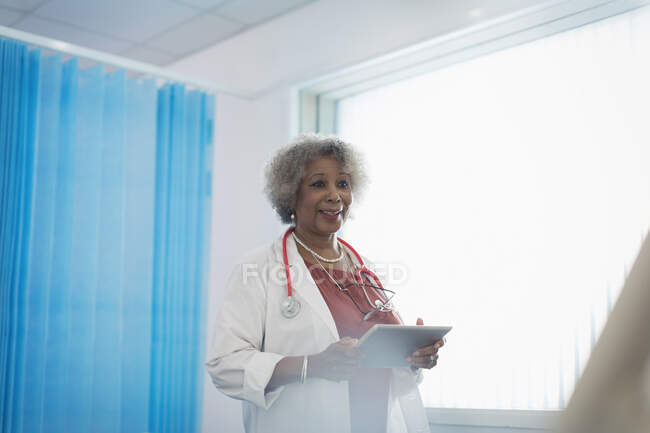 Senior female doctor with digital tablet making rounds in hospital room — Stock Photo