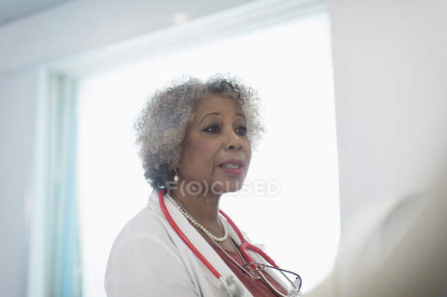 Médico senior haciendo rondas, hablando en el hospital - foto de stock