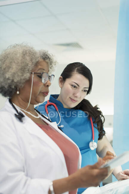 Doctora y enfermera con tableta digital hablando en el hospital - foto de stock