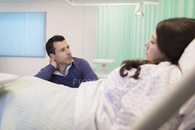 Hombre visitando esposa descansando en cama de hospital - foto de stock