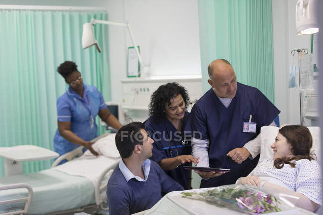 Médicos com tablet digital fazendo rondas, conversando com paciente em enfermaria hospitalar — Fotografia de Stock