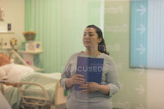 Female doctor with medical chart making rounds in hospital ward — Stock Photo