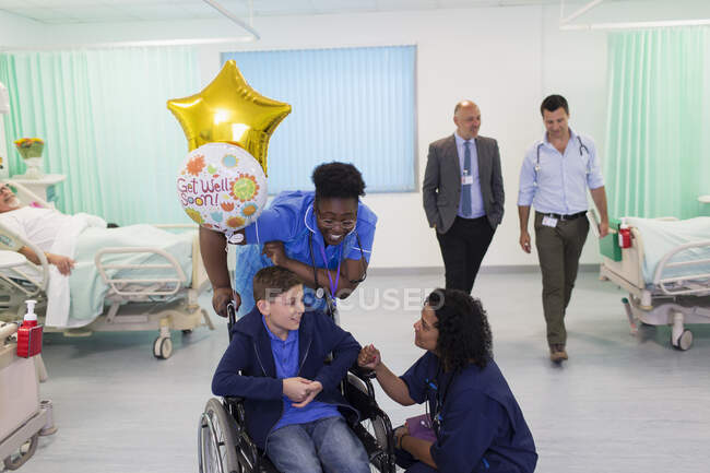 Médecin et infirmière parlant avec un patient garçon en fauteuil roulant dans la salle d'hôpital — Photo de stock