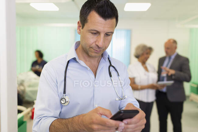 Médico masculino usando teléfono inteligente en la sala de hospital - foto de stock