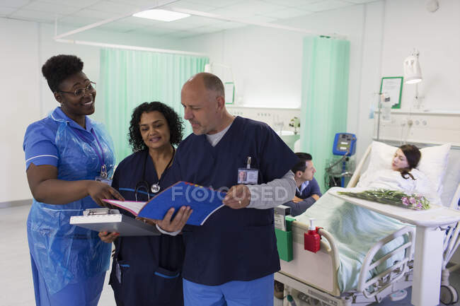 Лікарі й медсестра, які займаються медичною картою, роблять обхід, радиться у лікарняному відділенні. — стокове фото