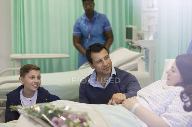 Visita familiar, conversación con el paciente en la sala del hospital - foto de stock