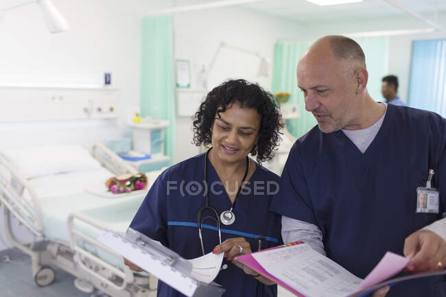 Doctors with medical charts making rounds, consulting in hospital ward — Stock Photo
