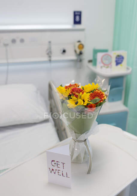 Flower bouquet and Get Well card on tray in vacant hospital room — Stock Photo