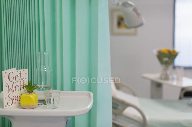 Get Well Soon card and water carafe on tray in vacant hospital room — Stock Photo
