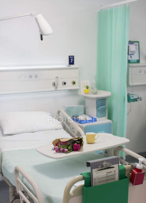 Flowers on tray over hospital bed in vacant hospital room — Stock Photo