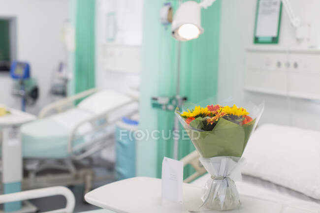 Buquê de flores e cartão de saudação na bandeja no quarto de hospital vago — Fotografia de Stock