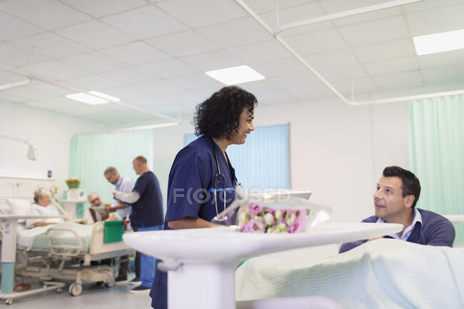 Doctor haciendo rondas, hablando con el visitante en la sala del hospital - foto de stock