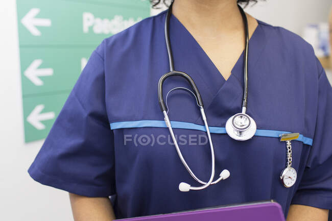 Primer plano médico femenino que usa matorrales y estetoscopio en el hospital - foto de stock