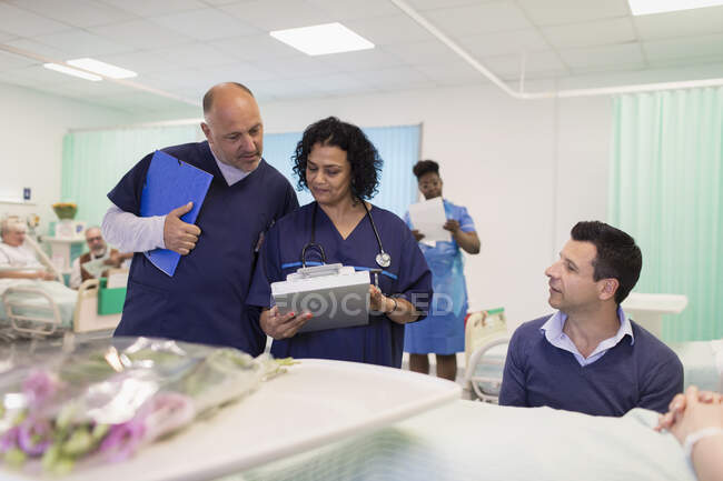 Médicos com ficha médica a fazer rondas na enfermaria do hospital — Fotografia de Stock