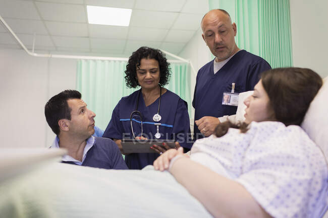 Doctors making rounds, talking with couple in hospital room — Stock Photo