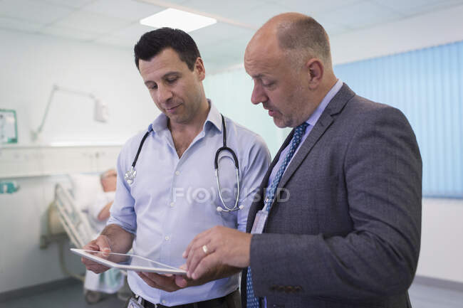 Médecins masculins avec tablette numérique faisant des rondes, consultation dans la chambre d'hôpital — Photo de stock