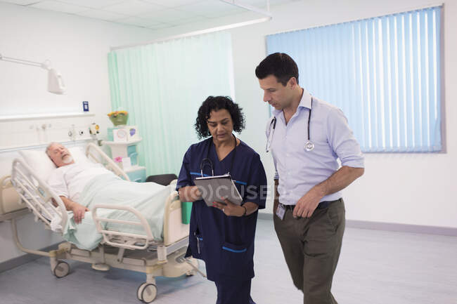 Médicos con tableta digital haciendo rondas, consultoría en habitación de hospital - foto de stock