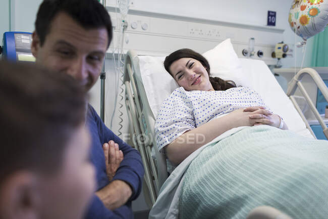 Усміхнений пацієнт, який відвідує сім'ю в лікарняній кімнаті — стокове фото