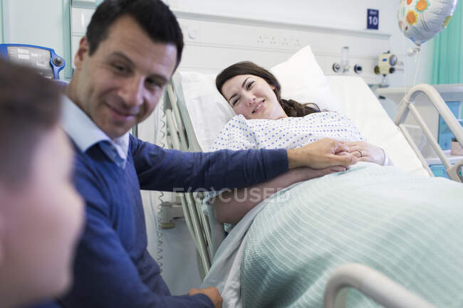 Familia cariñosa visitando al paciente en la habitación del hospital - foto de stock