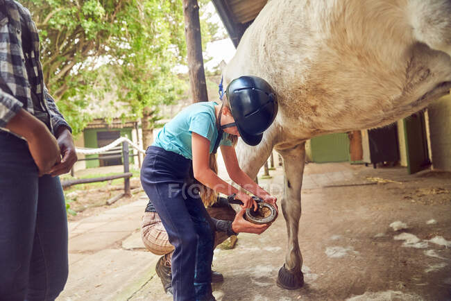 Menina limpeza cavalo casco fora estábulos — Fotografia de Stock
