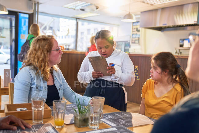 Young female server with Down Syndrome taking customer order — Stock Photo